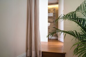 A hallway with a wooden floor, a beige curtain, and a plant on the right. - Charm and comfort in the heart of Taormina: 3 bedrooms and a private terrace (Taormina)