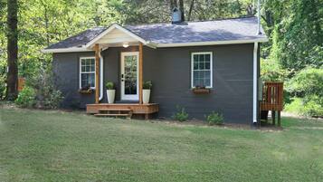 A small, single-story house with a front porch, a chimney, and a mailbox.