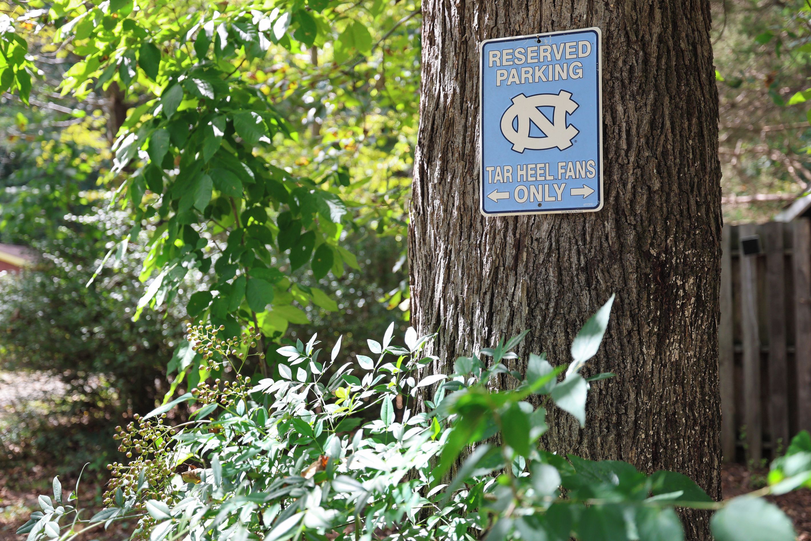 A sign on a tree indicating reserved parking for Tar Heel fans only.