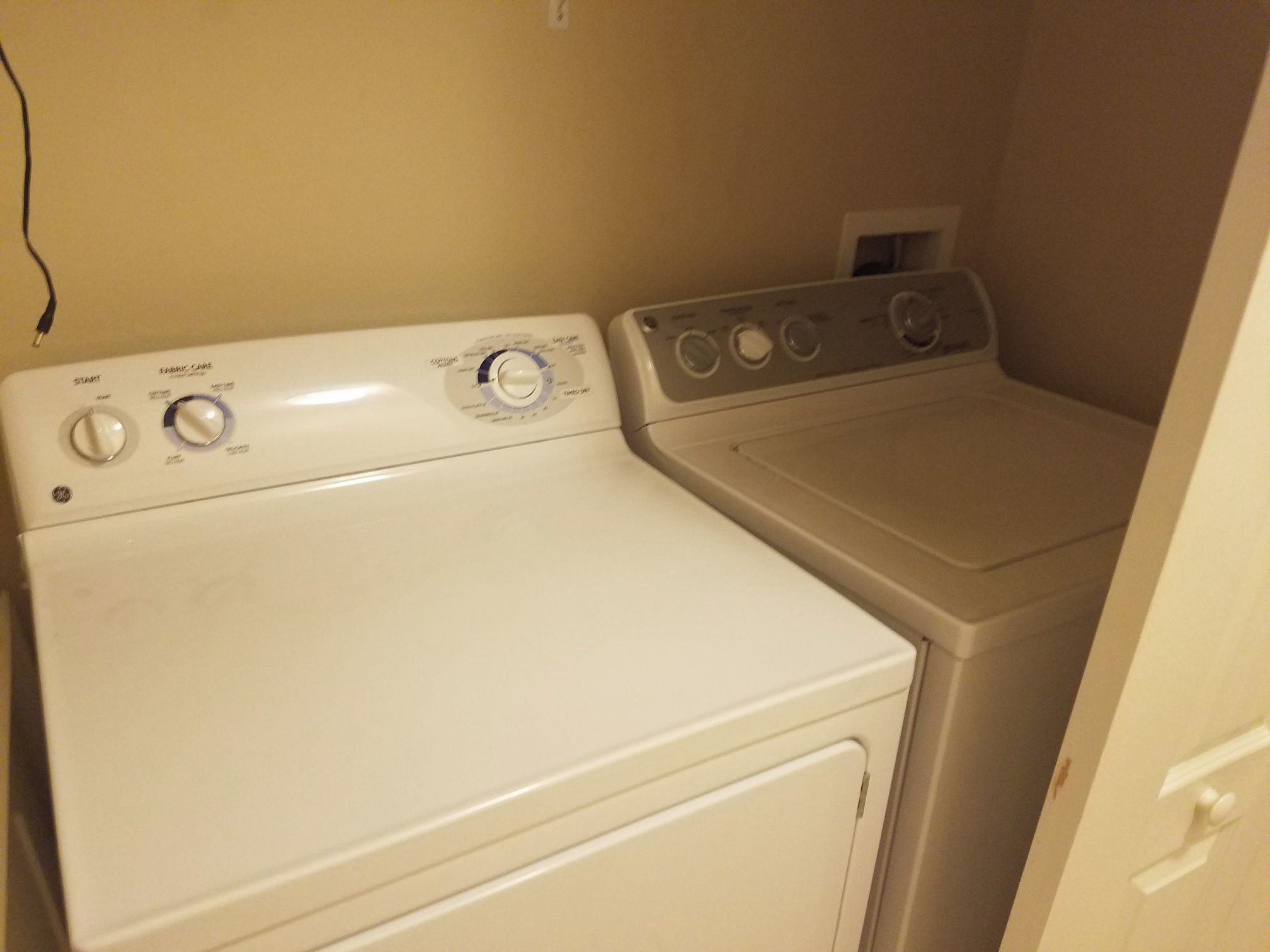 A compact, white, front-loading washer and dryer unit with multiple control knobs and a small vent on the top right.
