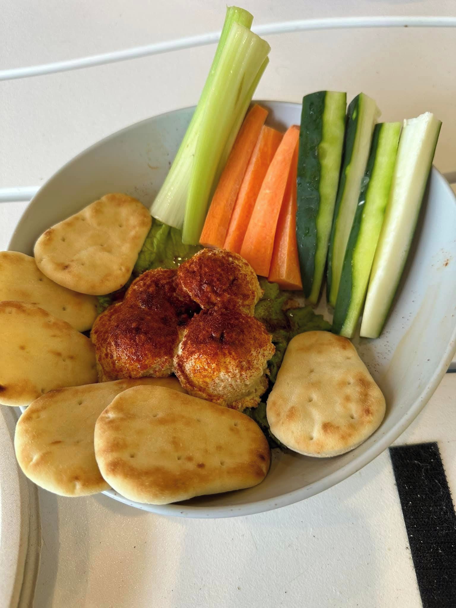 Un plato con alimentos, incluyendo pan, verduras y un trozo de carne.