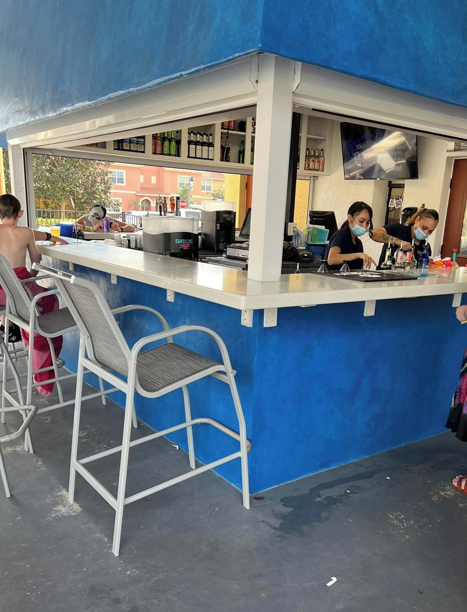Een bar met een toonbank, krukken en uitzicht op de straat.