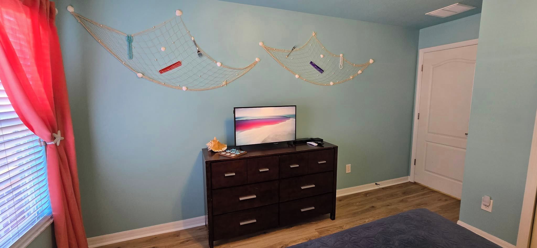Een kamer met een donkere houten dressoir, een schilderij en twee hangmatten aan de muur.
