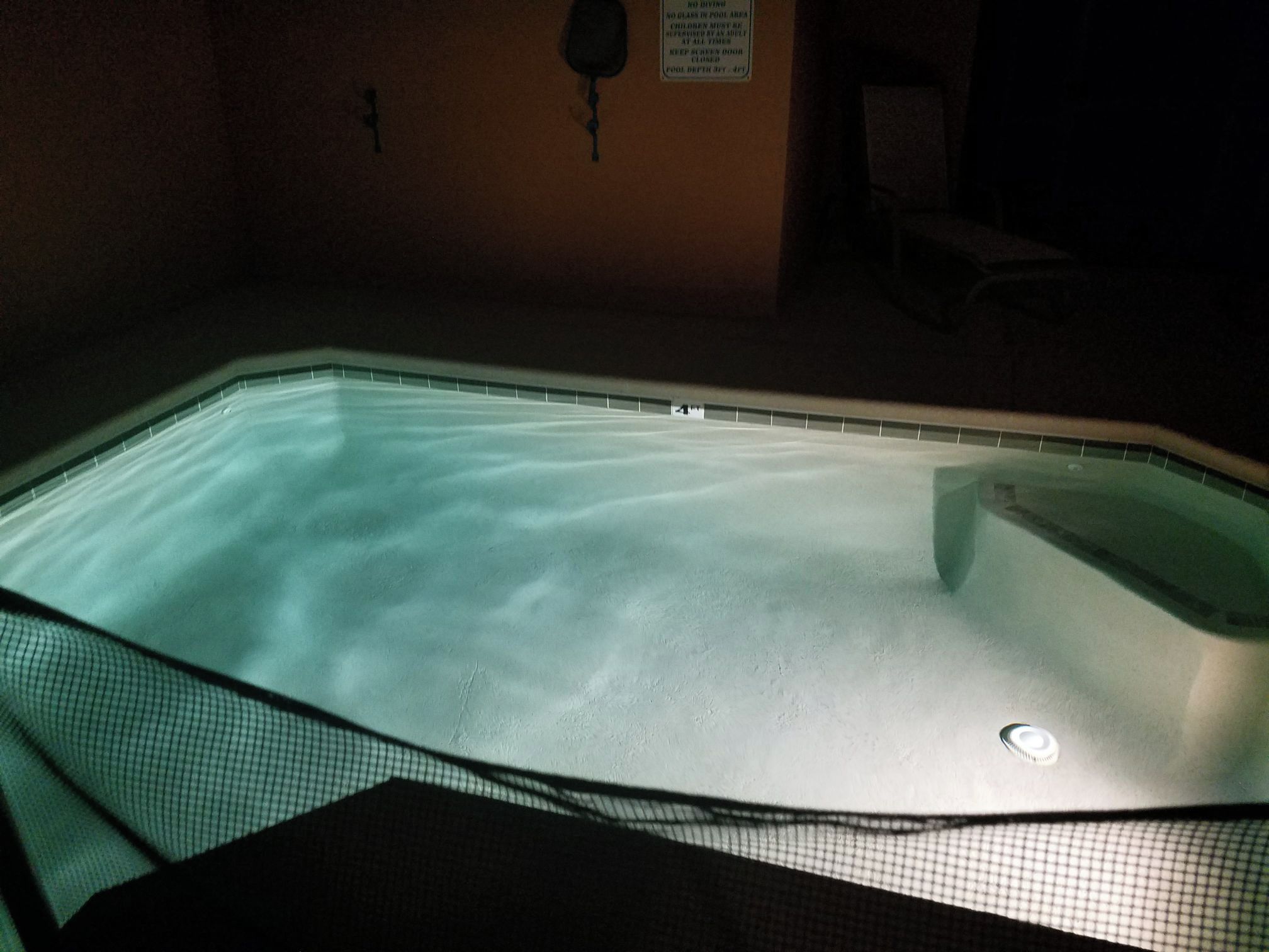 Una piscina con borde de azulejos y un letrero en la pared.