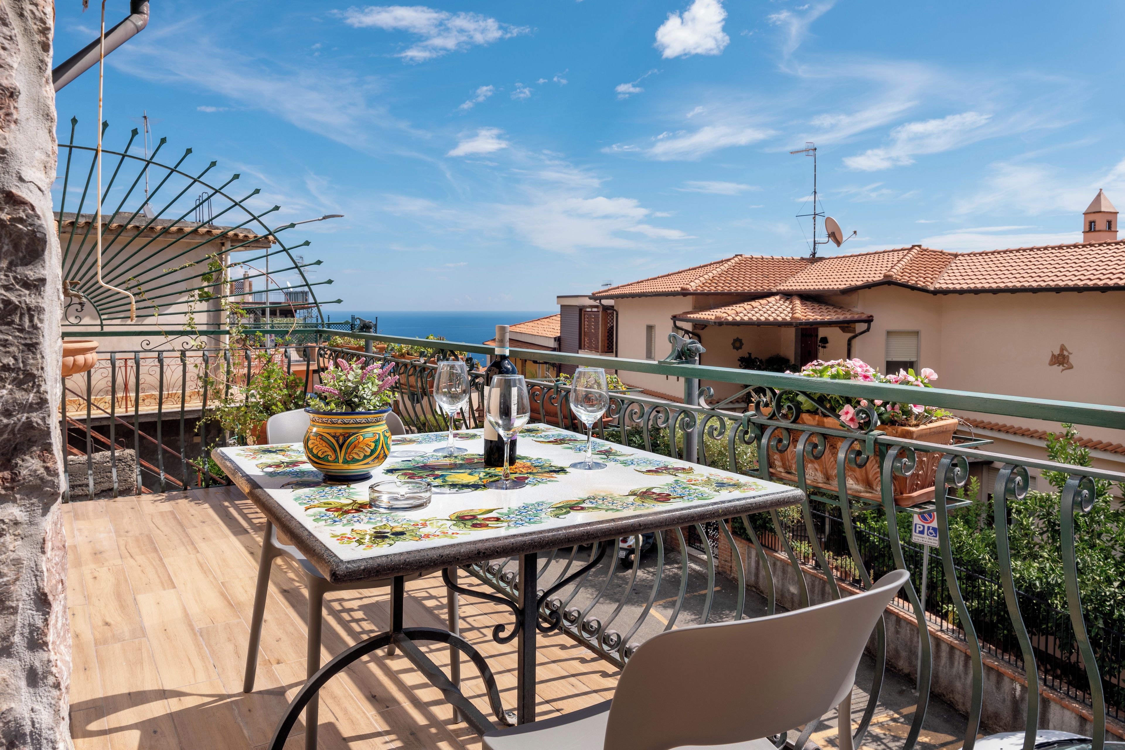 Un balcone con un tavolo apparecchiato per la cena, con vista sulla costa.