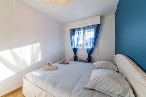 Ein Schlafzimmer mit Bett, einem Fenster mit Vorhängen und einer Wand-Klimaanlage.