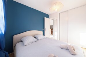 A bedroom with a bed, pillows, a bedside table, and a hanging light fixture. - Gabions - Proche plage - Balcon (Villers-sur-Mer)