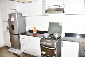 Een keuken met een koelkast, fornuis, oven en kastjes.