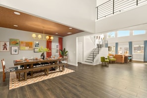 A spacious living area with a dining table, benches, and a staircase leading to an upper level. - Boots & Birdies -Sleeps 22- Luxury Pool+Spa, Pickleball, Golf Simulator, & more (Austin)