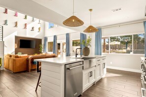 A modern kitchen with a central island, stainless steel appliances, and pendant lighting. - Boots & Birdies -Sleeps 22- Luxury Pool+Spa, Pickleball, Golf Simulator, & more (Austin)