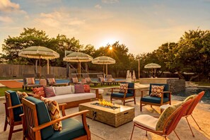 An outdoor patio area with a pool, lounge chairs, and umbrellas. - Boots & Birdies -Sleeps 22- Luxury Pool+Spa, Pickleball, Golf Simulator, & more (Austin)