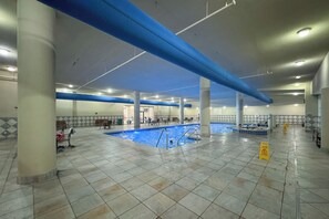 An indoor swimming pool with tiled flooring, blue structural beams, and a caution sign. - Phoenix West #1801 - New! Luxury Beachfront 4BR, Wraparound Balcony, Lazy River (Orange Beach)