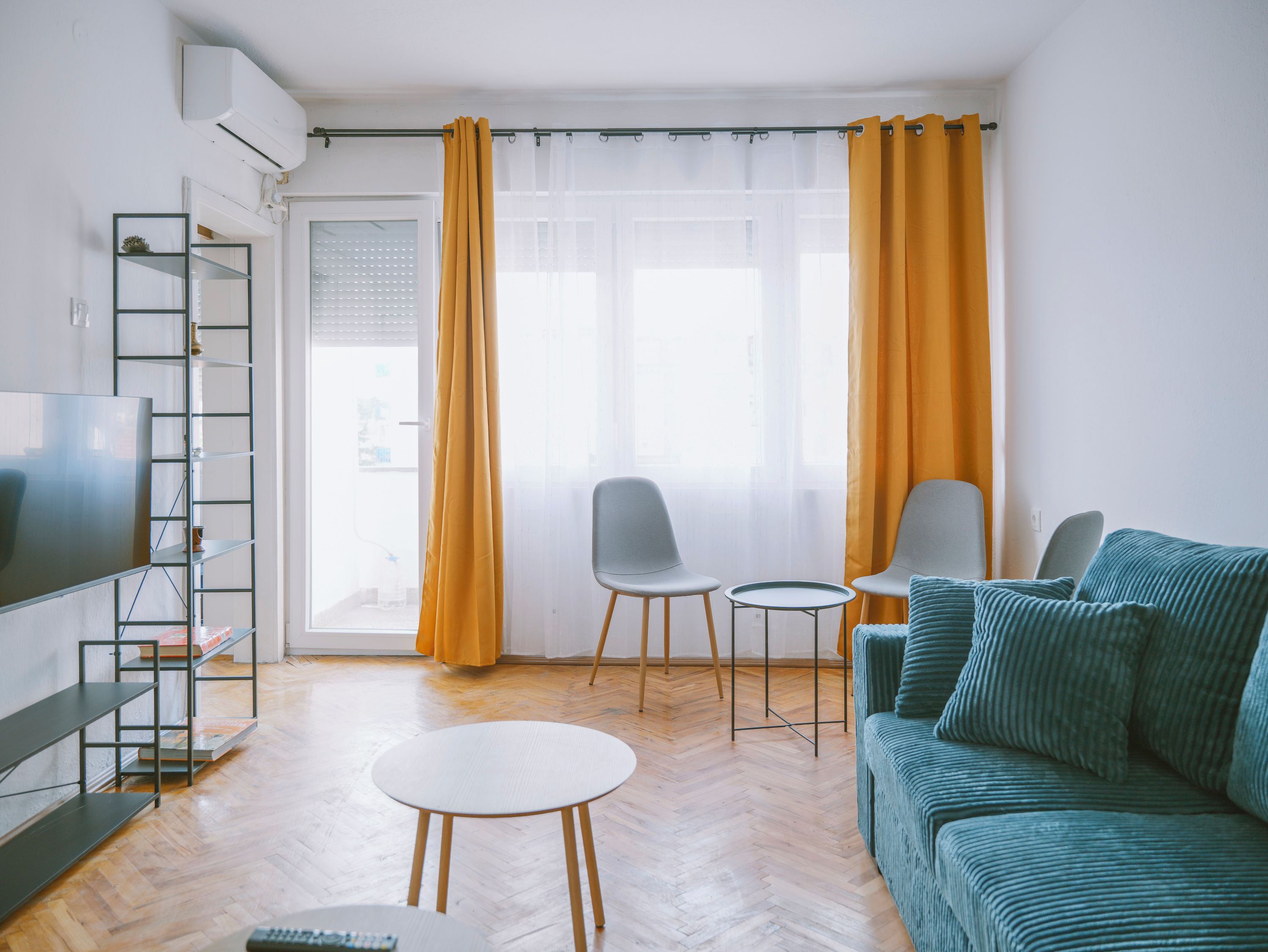 A living room with a sofa, two chairs, a small table, a TV, and a bookshelf.