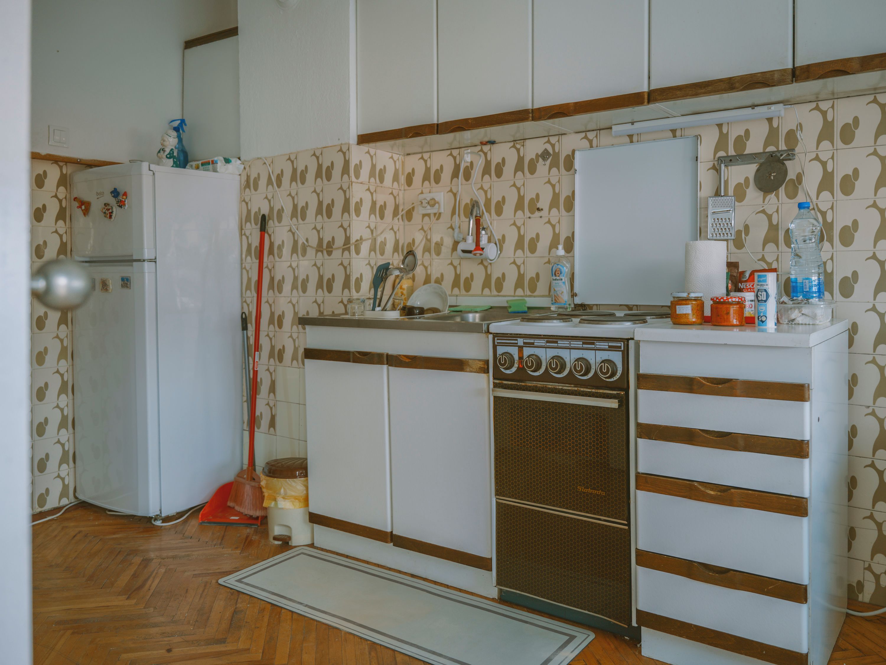 A kitchen with a refrigerator, stove, and cabinets.