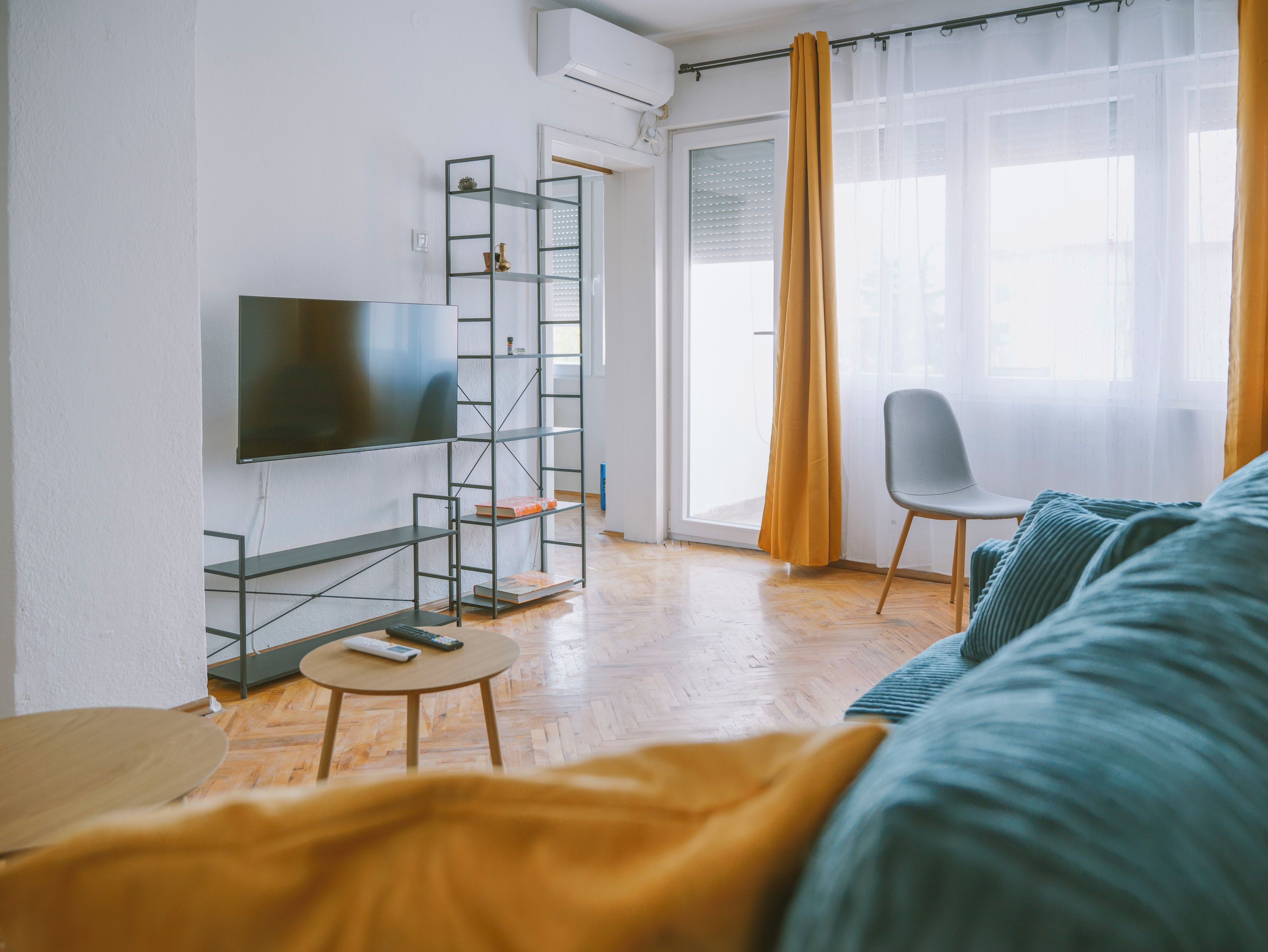 Een moderne woonkamer met een flatscreen televisie, een boekenkast, een ronde salontafel, een bank en een fauteuil.