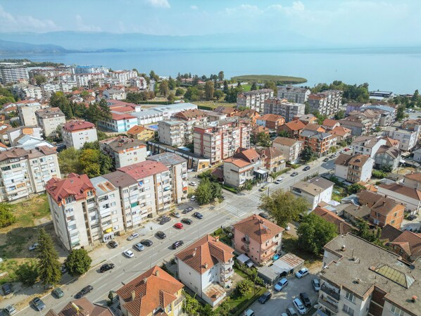 A residential area with multi-story buildings, a main road, and a body of water in the background.