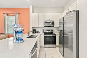A modern kitchen with white cabinets, stainless steel appliances, and a granite countertop. - Key Lime Dream Cottage near Disney | Margaritaville & Waterpark Access - 3074KL (Kissimmee)