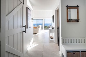 A modern interior with a view to the sea, a white sofa, and a minimalist design. - L'Aquarelle : Riverfront Home, 180° View & Hot Tub (Saint-Irénée)