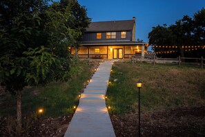 A house with a pathway leading to the entrance, surrounded by trees and a grassy area. - Private 10-Acre Estate · Heated Pool · Sleeps 24 (Fredricksburg)