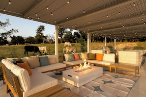 An outdoor patio with a white sofa set, a fire pit, and string lights. - Private 10-Acre Estate · Heated Pool · Sleeps 24 (Fredricksburg)