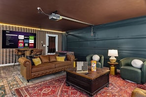 A living room with a brown leather sofa, a coffee table, and a TV mounted on the wall displaying various streaming services. - Private 10-Acre Estate · Heated Pool · Sleeps 24 (Fredricksburg)