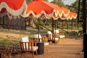 Outdoor seating with wooden chairs and a large orange umbrella. - Romantic Hill Country Cottage w/ Private Hot Tub (Fredricksburg)