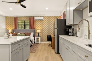 A modern kitchen with grey cabinets, a black refrigerator, and a white countertop. - Romantic Hill Country Cottage w/ Private Hot Tub (Fredricksburg)