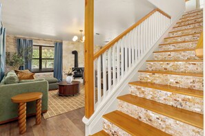 A staircase with wooden steps and white balusters, leading to a landing with a stone wall. - 40-ft Heated Pool & Spa, Sport Court, Game Room (Fredricksburg)
