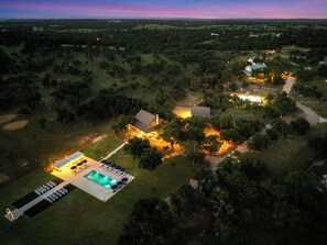 An aerial view of a property with a swimming pool, lounge area, and multiple buildings. - 40-ft Heated Pool & Spa, Sport Court, Game Room (Fredricksburg)