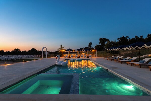 A swimming pool with a swan float, lounge chairs, and a gazebo with string lights. - 40-ft Heated Pool & Spa, Sport Court, Game Room (Fredricksburg)
