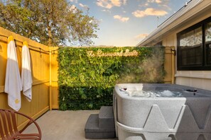 A hot tub with a sign reading 'The Rosewood Suite' in a backyard with a wooden fence and greenery. - Cozy Hill Country Cottage · Private Hot Tub (Fredricksburg)