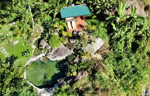A house with a green roof, surrounded by lush greenery and a small pond. - Casa Nanita | Chirripó riverfront mountain retreat (Perez Zeledon)
