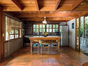 A kitchen with a wooden ceiling, a central island, and a refrigerator. - Casa Nanita | Chirripó riverfront mountain retreat (Perez Zeledon)