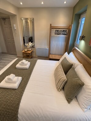 A hotel room with a large bed, a wooden headboard, a bedside table with a lamp, a mirror, and a window. - Burton House|4 Bed|Sleeps8|Private Parking (Wool)
