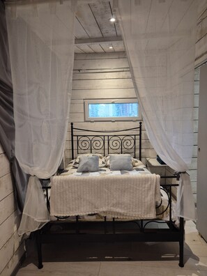 Ein Bett mit Baldachin, ein Fenster und Blick ins Freie.