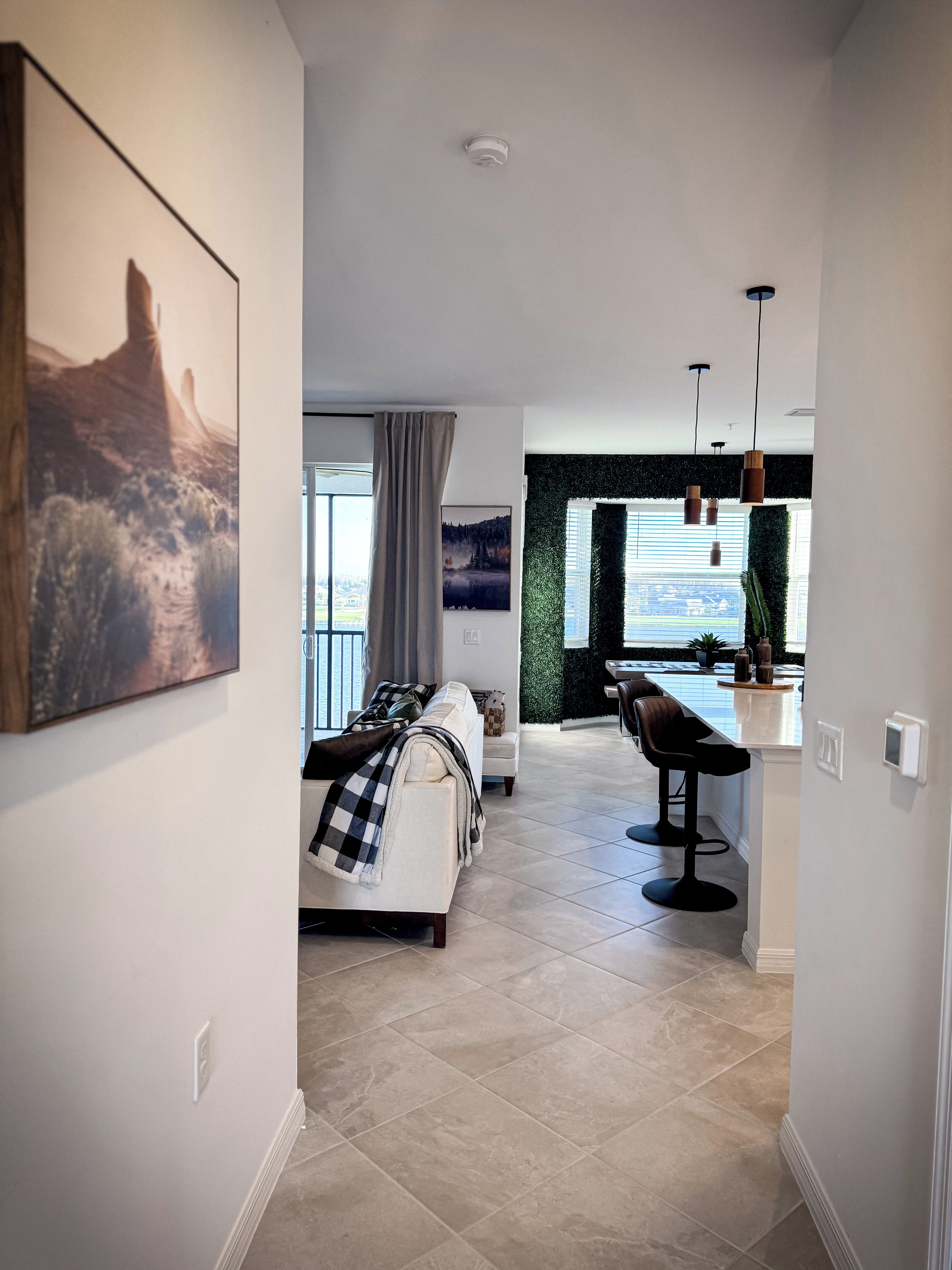 A modern interior with a bed, a dining area, and a view through a window.