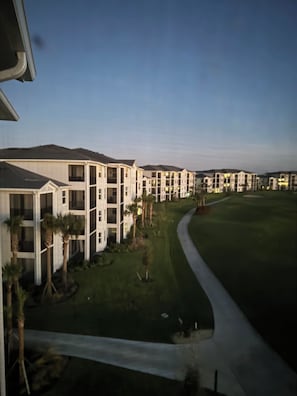 Complejo residencial con varios edificios de apartamentos, un césped cuidado y una entrada de acceso en curva.