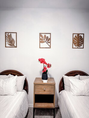 A hotel room with two beds, a nightstand with a vase of flowers, and wall art. - Luxury Golf Penthouse Verdanza (Ave Maria)