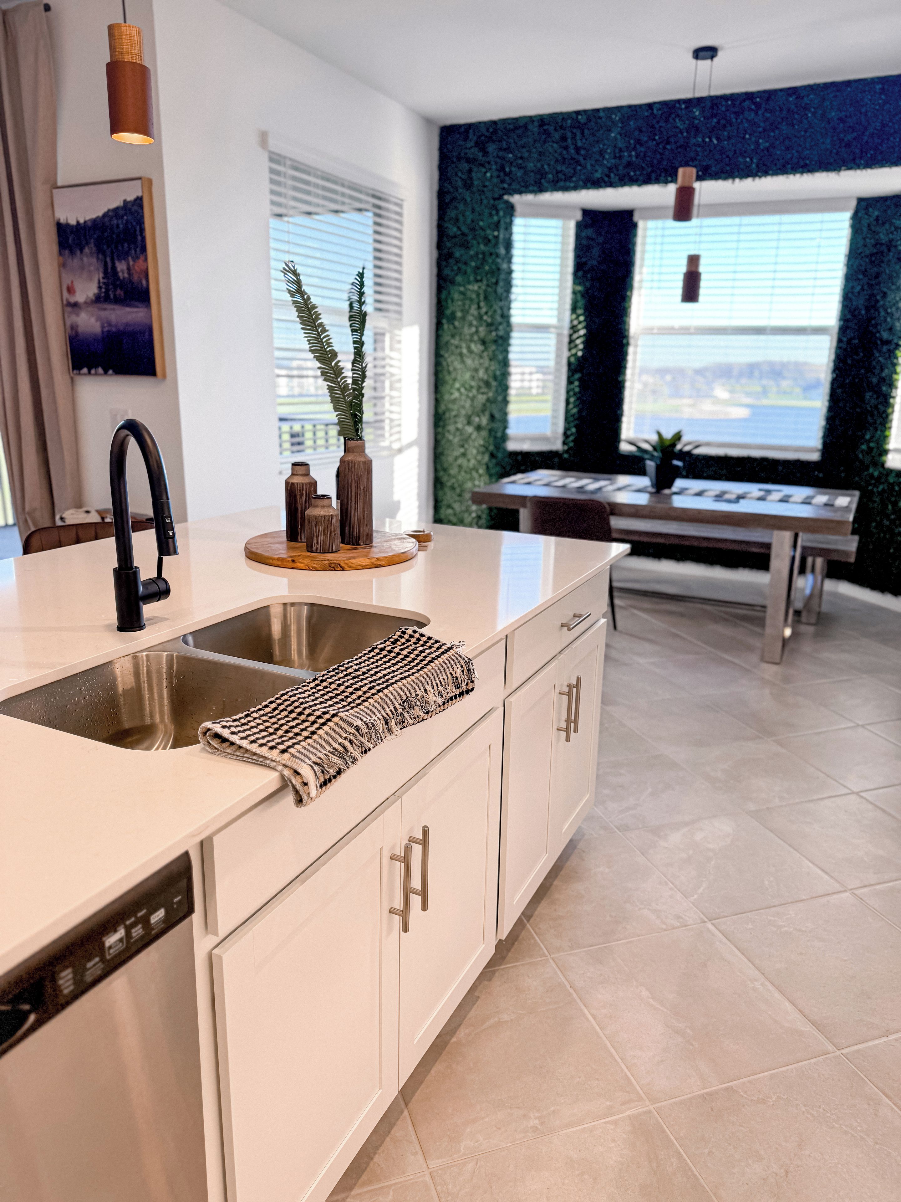 A modern kitchen with a large island, stainless steel sink, and a dishwasher.