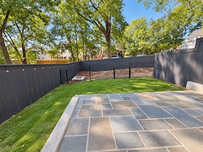 A backyard with a stone patio, a fenced area, and a lawn. - Homewood Luxury 2 Bedroom 2.5 Bath Townhome 3018 (Homewood)