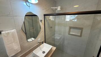 A modern bathroom with a glass-enclosed shower, a white sink, and a large mirror.