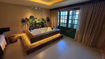 Un baño moderno con una bañera grande, una plataforma de madera y vistas al exterior a través de una ventana.
