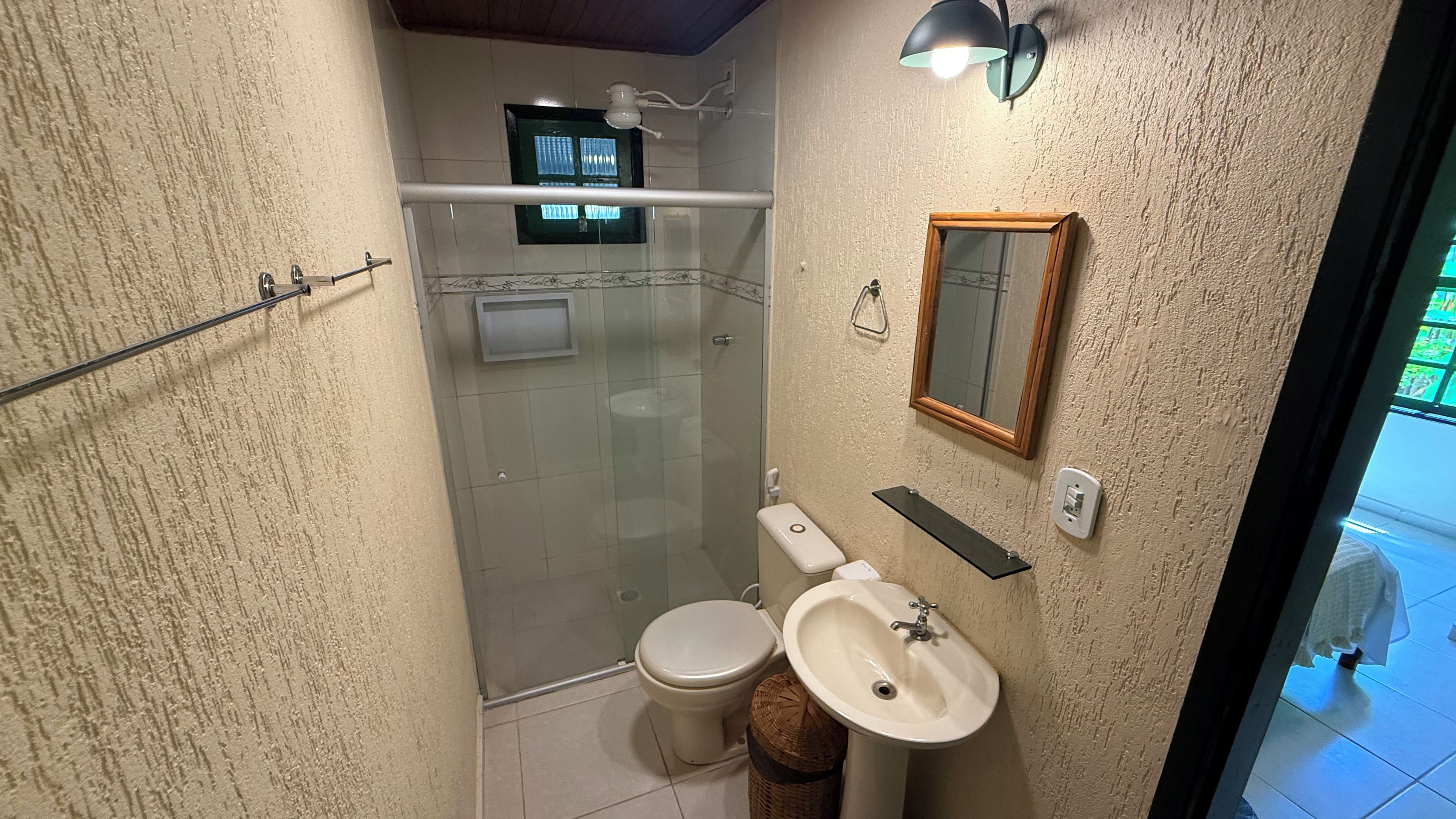 Ein Badezimmer mit Duschkabine, Toilette, Waschbecken, Spiegel und Handtuchhalter.