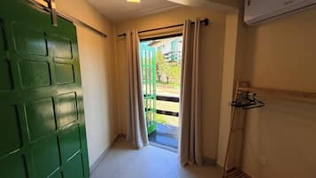 Un pasillo con una puerta verde, un ventanal corredero y un perchero.