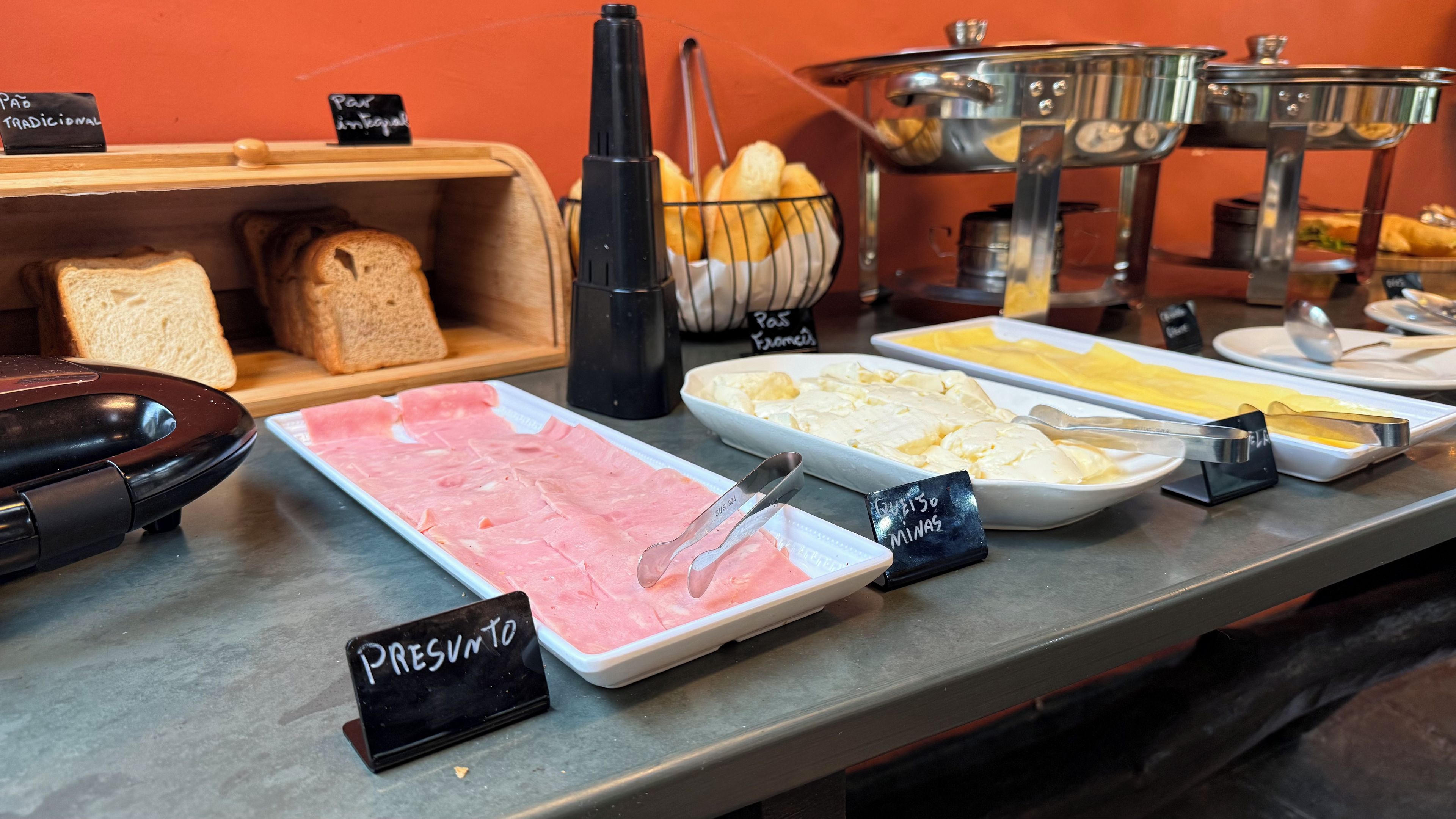 A buffet with various food options including meats, cheeses, and bread.