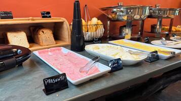 A buffet with various food options including meats, cheeses, and bread.