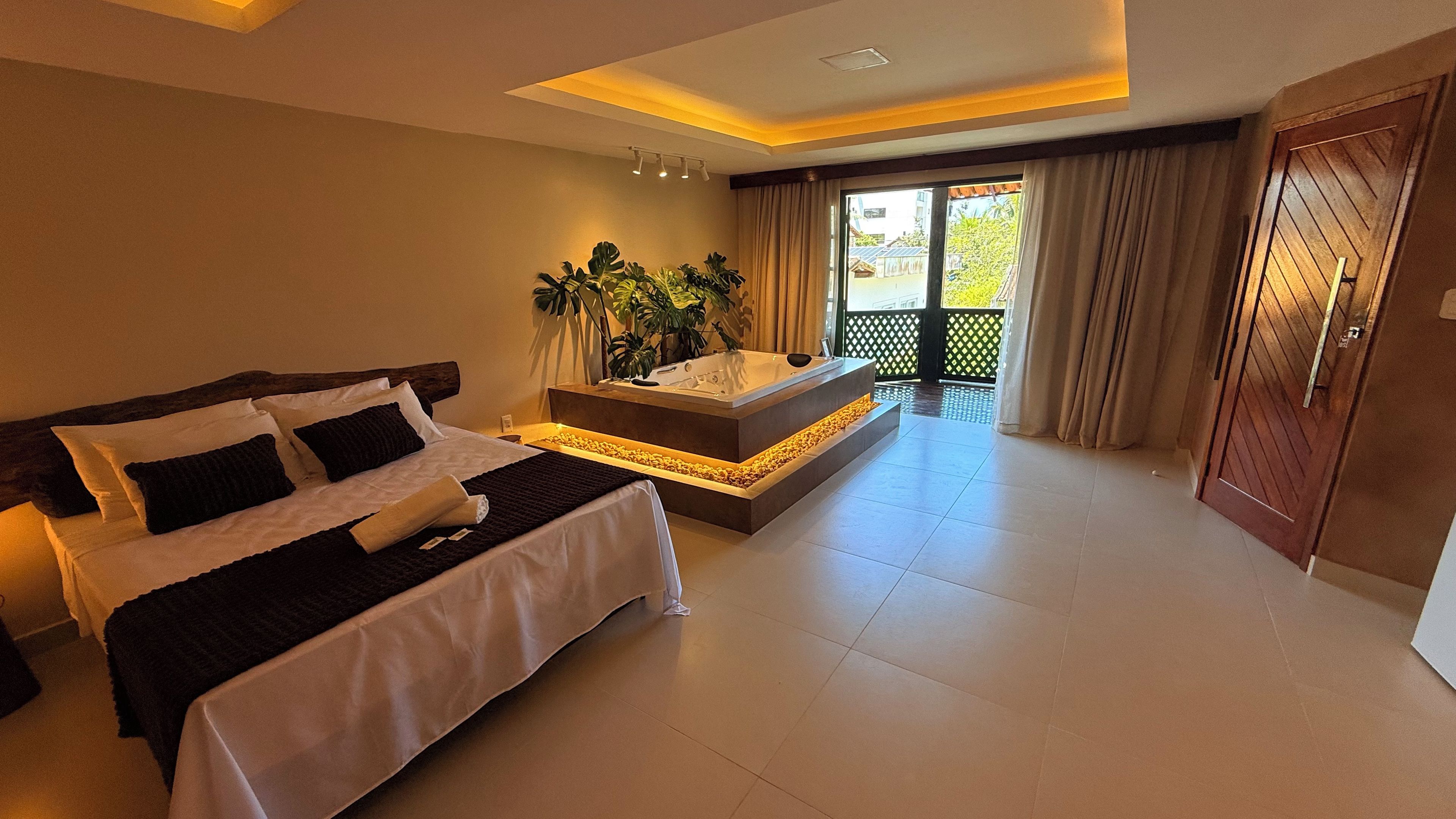 A hotel room with a bed, a seating area with a bathtub, and a view of the outside.
