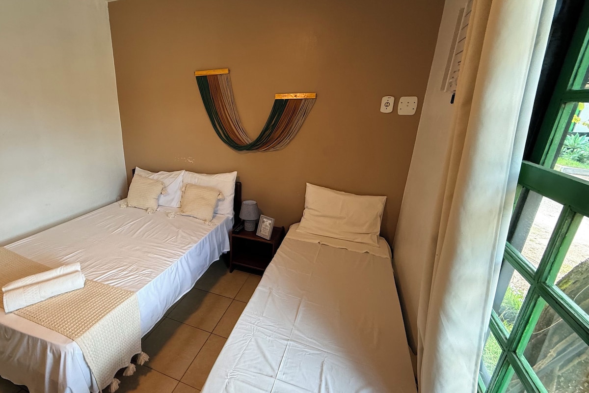 A room with two single beds, a small bedside table with a lamp, and a wall-mounted decorative item.