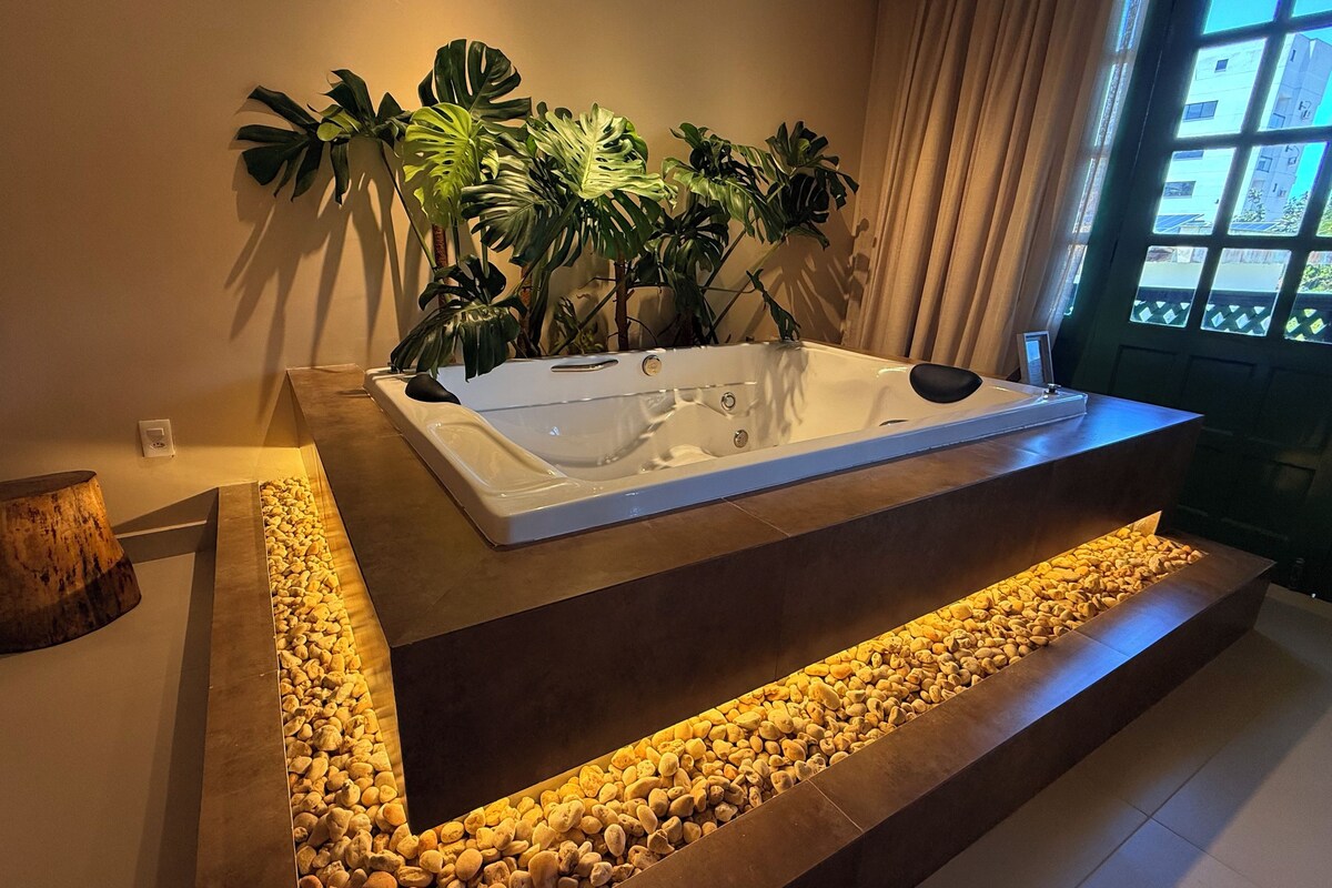Un área de spa con un jacuzzi, una planta y un banco de madera.