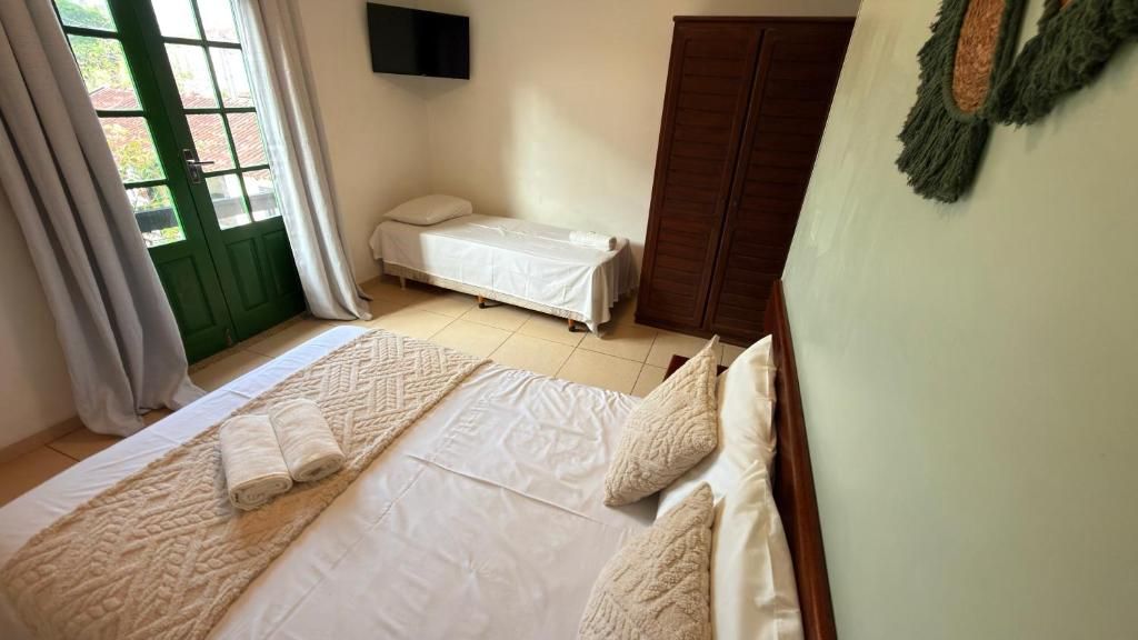 A bedroom with a large bed, a smaller bed, a wardrobe, and a television on the wall.